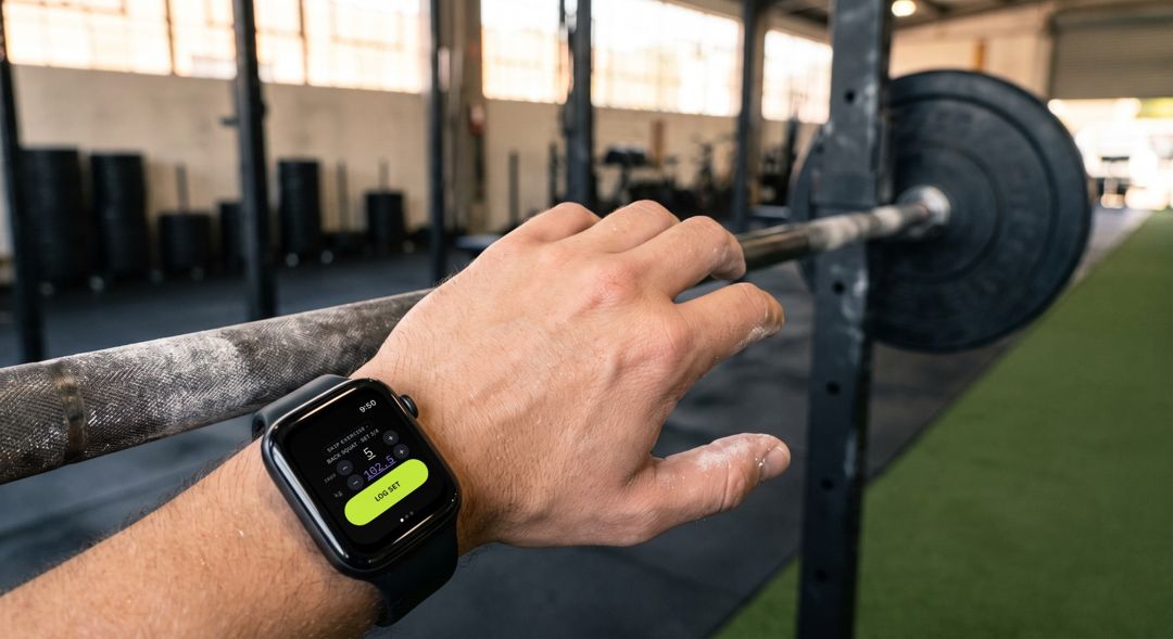 An athlete's wrist at the squat rack, Threshold's Log set screen on the Apple Watch.